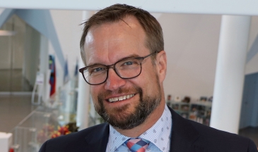 Portrait of a man wearing a suit and glasses with a patterned shirt and tie