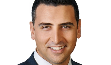 Headshot of a man wearing a charcoal suit and deep purple tie