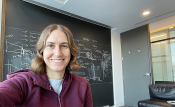 Woman in office sitting in front of chalkboard of equations