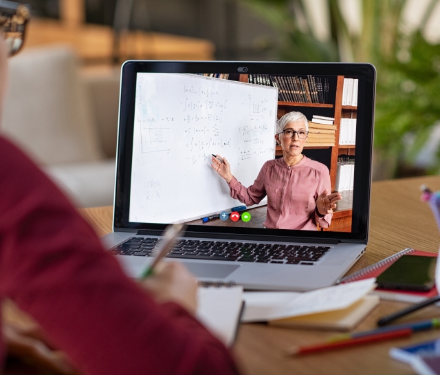 Woman doing a virtual class and teacher on computer screen teaching