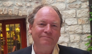 Portrait of a man in a suit sitting outside at a restaurant