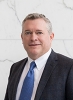 Portrait of a man wearing a grey suit and blue tie