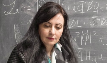 Portrait of a woman reading a book sitting in front of a blackboard