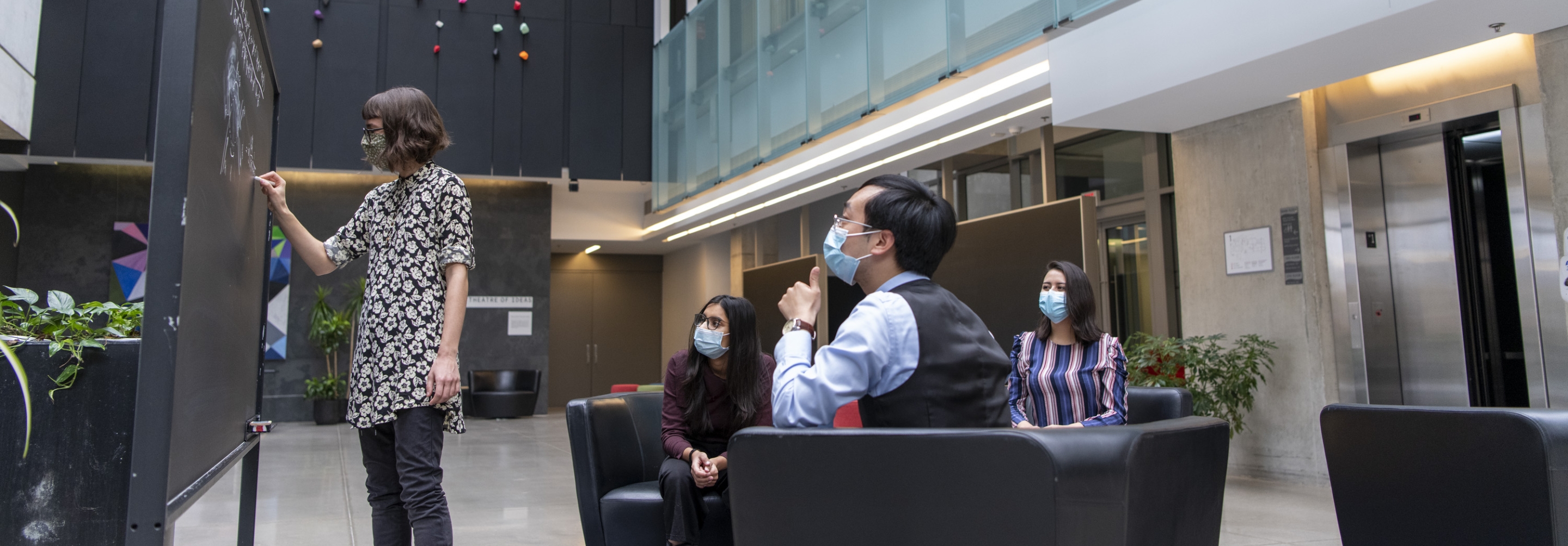 Group of students wearing masks working at a blackboard together