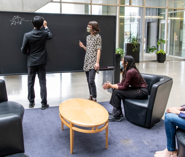 Group of students wearing masks working at a blackboard together