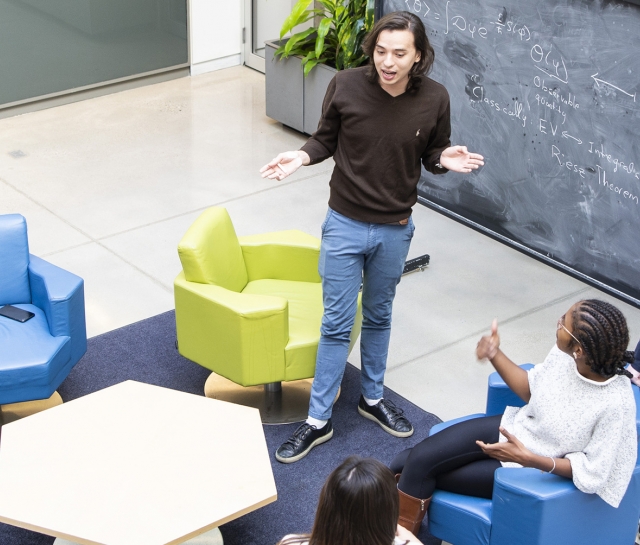 Students talking in a group around a chalkboard