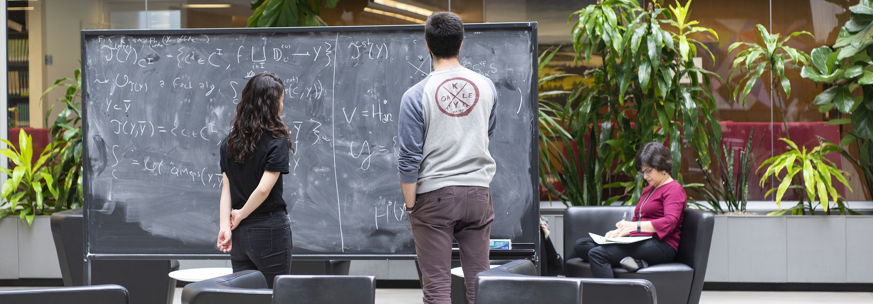 Man and women working at blackboard together in atrium