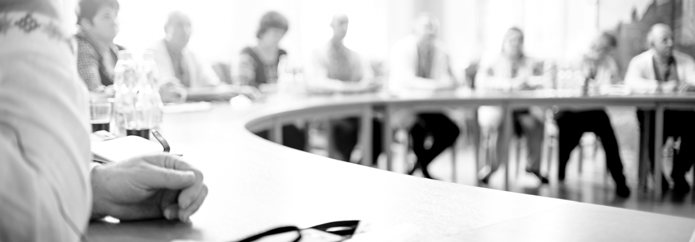 Black and white photo of people sitting around a curved table